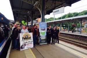 Members of FolkEast, the Young'uns, and the East Suffolk Lines Community Rail Partnership launch the FolkEast Festival and rail-bus link at Ipswich station. A member of staff from Abellio Greater Anglia tries his hand on the melodion!