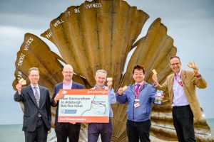 Members of the East Suffolk Lines Community Rail Partnership and representatives from First Eastern Counties and Greater Anglia launch the new Aldeburgh rail/bus through ticket in front of the scallop at Aldeburgh beach